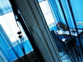 закрытые двери на балкон с компьютерным столиком в молодежной евро квартире высотного здания