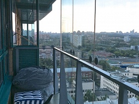банкетка с полосатым матрасом на открытом балконе квартиры на 22 этаже