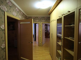прихожая со шкафами и полками под стеклом в длинном коридоре с цветочными обоями трехкомнатной актерской квартиры