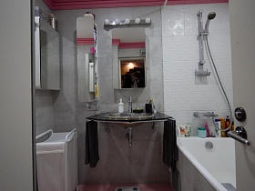 белая ванна, настенные шкафчики, зеркало над раковиной в ванной комнате современной трехкомнатной квартиры в светлых тонах