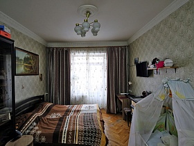 коричневые шторы и белая гардина на окне светлой спальной комнаты с большой коричневой кроватью у стены с картиной трехкомнатной квартиры на шестом этаже сталинского дома