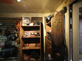 вымпелы, сумки, часы, секундомеры, кепки и шлемы на полках деревянных открытых шкафов в магазине мотошмоток для съемок кино