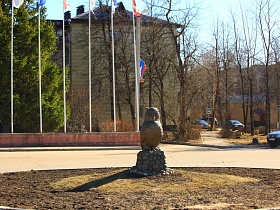 огромная статуя совы на пьедестале из камня в центре круглой клумбы на кольцевом перекрестке в Сычево для съемок кино