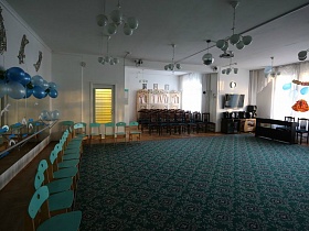 стулья для зрителей и участников в просторной сценической комнате с мягким ковром и большими окнами