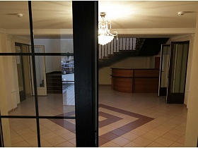 вид на светлый просторный холл дома отдыха через стеклянную входную дверь