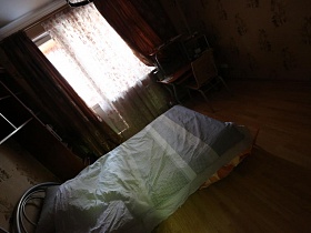 большая кровать с металлической спинкой под светлым одеялом в спальной комнате актерской трехкомнатной квартиры