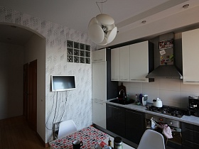 белый чайник на встроенной газовой плите, раковина с моющими средствами, электроприборы на светлой столешнице под мрамор современной мебельной кухни
