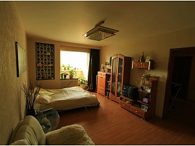 коричневая штора, и орнамент на стене спальни, совмещенной с застекленным балконом в современной трехкомнатной квартире
