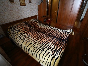 леопардовое покрывало на деревянной кровати в спальне обычной трешки стандартного дома