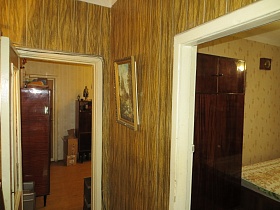 картина в рамке на стенах, выполненных под дерево прихожей с открытыми дверьми в гостинную и спальную комнату квартиры СССР