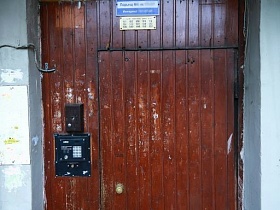 домофон, вывеска с номером подъезда и квартир на входной деревянной двери сталинского здания с полисадником и пандусом