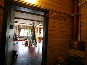 перекидной календарь и тремпеля на трубах в прихожей современного загородного дома с открытой дверью в просторную гостиную