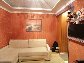 картина над бежевым угловым диваном в детской комнате с ораньжевыми стенами в квартире с выходом на крышу магазина