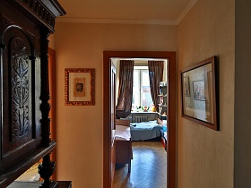 картины на бежевых стенах прихожей у открытой двери в детскую комнату квартиры художника в сталинке