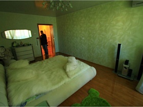 зеленый коврик у белой кровати и колонки муз центра в спальной комнате обычной двушки в Долгопрудном