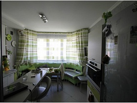 зеленые шторы на эркерном окне зеленой кухни  в двухкомнатной квартире новостроя