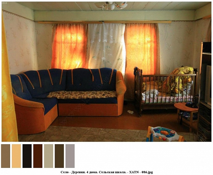 синий с ораньжевым угловой мягкий диван  и детский манеж у окна с белой гардиной и ораньжевыми шторами в гостиной со светлыми обоями жилого дома на селе