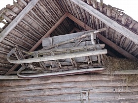 деревянные сани с полозьями под крышей деревянной постройки в заброшенной деревне