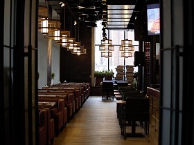 индивидуальное освещение над столиками с мягкими креслами на светлом коричневом полу стильного крафтового ресторана