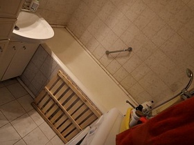 белая раковина со шкафчиком, зашитая ванна,стиральная машинка в ванной комнате с белой плиткой сталинской квартиры