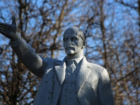 фигура Ленина с устремленным вперед взглядом и вытянутой рукой для приветствия на постаменте в городке Сычево
