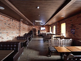 общий вид длинного зала пиццерии с кирпичными стенами, коричневым потолком и индивидуальными столиками в спальном районе