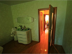 зеркало над белым комодом и мягкая игрушка на пуфике в углу светлой спальни в простой двушке в Долгопрудном