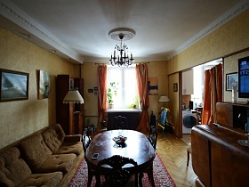 деревянная и мягкая мебель у желтых стен гостиной с белым потолком советской трехкомнатной квартиры