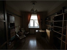бежевые шкафы с многочисленными вещами, обувью на полках, креслами, письменным столом и комодом в комнате с белым потолком и бежевыми обоями простой квартиры для съемок кино
