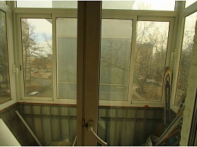 лыжи на застекленном балконе типичной двухкомнатной квартиры в жилом доме