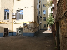 разрисованный угол желтого жилого дома в хитром дворе с многочисленными поворотами в центре города