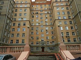 лестница с перилами и пандусом к высотному кирпичному жилому сталинскому дому