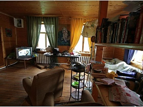 телевизор в углу на столике, длинный стол, мягкая мебель, этажерка в гостиной деревянной дачи музыканта