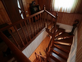 этажерка с книгами на лестничной площадке второго этажа с деревянной витой лестницей классической семейной дачи