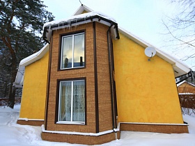 окна в два этажа в эркерной части торца желтой дачи в зимнем сосновом лесу