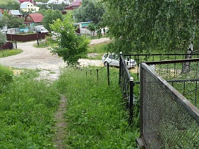 узкая тропинка среди густой зеленой травы, высокая береза на обочине дороги у возвышенности с могилками на Домодедовском кладбище недалеко от населенного поселка