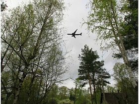 низко пролетающий самолет в небе над поселком с дачными домами