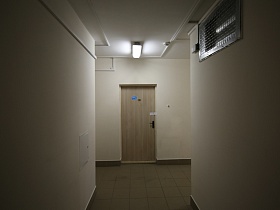 лампы дневного света на белом потолке, квадратная плитка на полу длинного коридора на первом этаже жилого дома в Котельниках