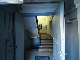 открытые двустворчатые входные двери в холл подъезда с квадратной плиткой на полу, почтовыми ящиками на стене и лестничными пролетами