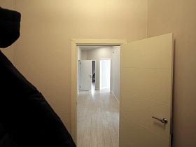 открытая дверь из коридора в светлых холл с лестницей