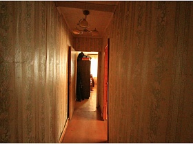 длинный коридор с полосатыми обоями на стенах и люстрой на потолке