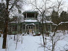 советская деревянная дача художника с овальной террасой на просторном участке с деревьями под снегом