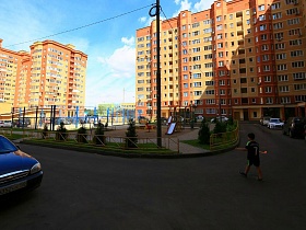 современный ухоженный двор со спортивной , детской игровой площадкой , зелеными насаждениями в центре высотных многоэтажек