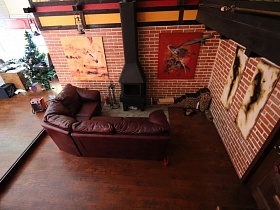 комната отдыха с коричневым мягким диваном и картинами на стене под кирпич