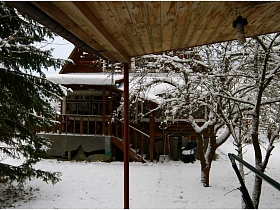 вид на открытую террасу с лестницей соседней бревенчатой дачи на зимнем участке