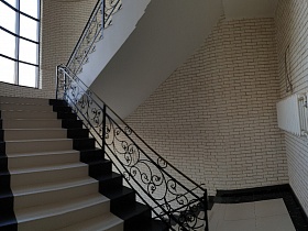 высокие окна на лестничных площадках и системы отопления на кирпичных стенах современного стильного подъезда жилого дома