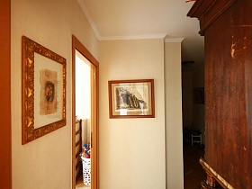 картины в рамках на бежевых стенах светлой прихожей стильной квартиры художественного образца в сталинке