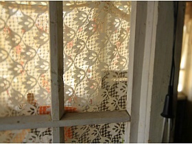 электрокипятильник на белой деревянной лутке дверного проема у окна,занавешенного тюлевой гардиной