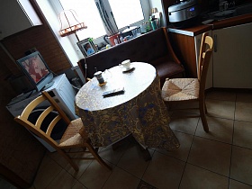 диван, стулья вокруг круглого обеденного стола с клеенкой, телевизор на стиральной машинке на кухне трехкомнатной семейной квартире времен СССР