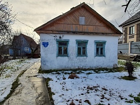 Одноэтажный дом-мазанка с побеленными стенами на заснеженном участке с асфальтированной дорожкой в Красногорске для съемок кино